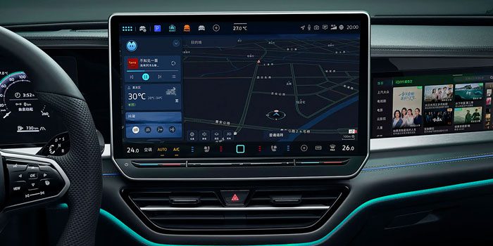 Close-up of a car's infotainment system with a large touchscreen displaying navigation, climate controls, and media options, alongside a digital dashboard, emphasizing advanced in-car technology.