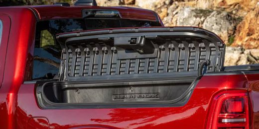 Display The RamBox Cargo Management System with its lid open, on a red 2026 Ram 1500 Tungsten 4x4 Crew Cab.