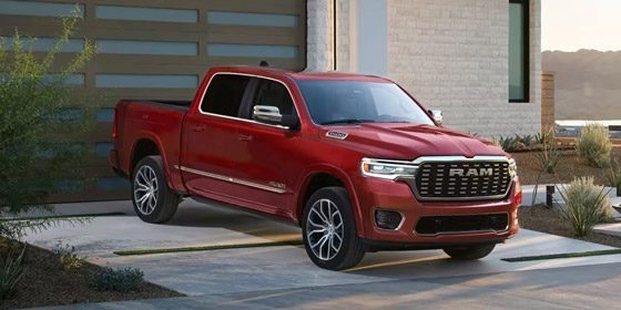 Display A red 2026 Ram 1500 Tungsten 4x4 Crew Cab parked in the driveway of a contemporary home.