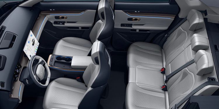 Top view of a car’s interior: light/black leather seats, digital screen, blue accent lights, and center console.
