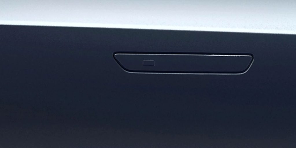 Sleek, recessed door handle (with a small button) on a dark car body, featuring a minimalist, modern design.