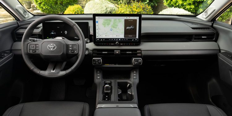 Modern Toyota vehicle interior with a minimalist black design, featuring a central touchscreen displaying navigation and a digital dashboard.