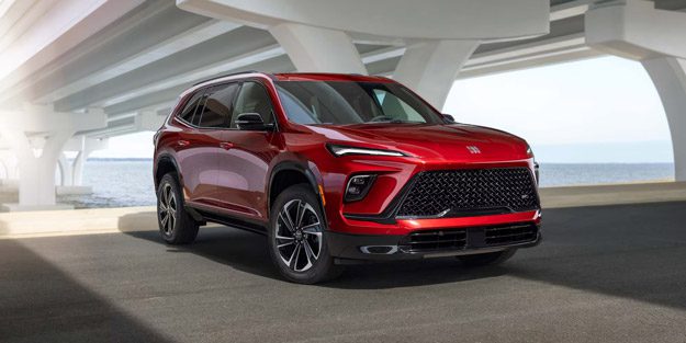 Red Buick SUV: Striking modern crossover with a bold black mesh grille and sleek LED headlights, showcased under a coastal bridge.