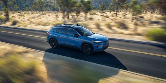 Buick electric SUV: Striking blue EV cruising on a desert highway amid Joshua Tree’s iconic landscape.