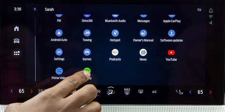 A driver's hand reaching out to touch an icon on the center display of a 2026 Ford Explorer SUV