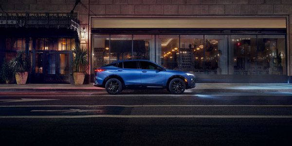 Side View of a Blue 2026 Buick Envista Sport Touring Sport SUV Driving Through Downtown at Night
