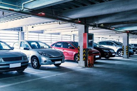 Indoor parking garage: Mixed modern cars parked safely in a multi-level concrete parking structure in the city.