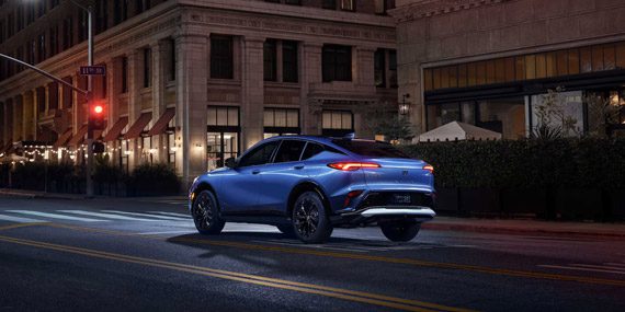 Three-quarters Rear View of the 2026 Buick Envista Driving Down Through the City at Night