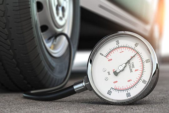 Close-up of a tire pressure gauge showing reading, connected to a car wheel, monitoring air pressure for vehicle maintenance and safe driving.