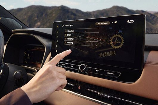 Hand interacting with the display in the 2026 Mitsubishi Outlander SUV, highlighting the dynamic Yamaha sound system.