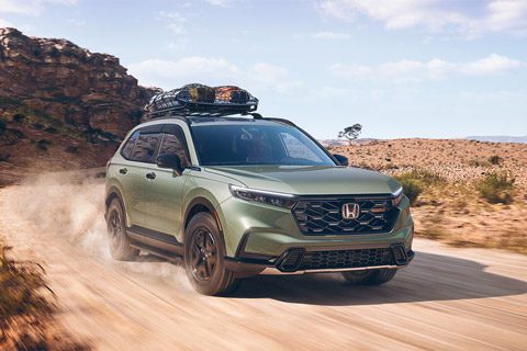 The 2026 Honda CR-V Trailsport Hybrid is driving on a dirt road
