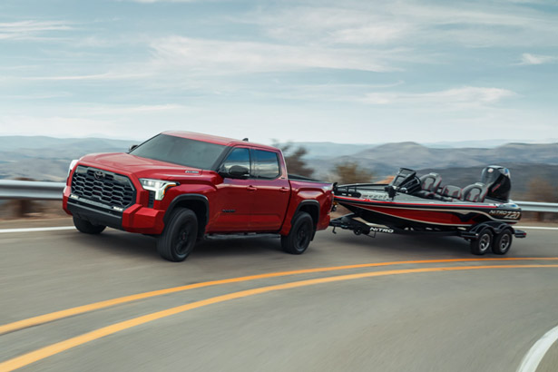 A red 2026 Toyota Tundra towing a small boat